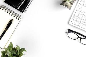 vue de dessus du bureau blanc moderne avec clavier d'ordinateur, page de cahier vierge et autres équipements sur fond blanc. concept d'espace de travail, style de gestion de l'espace de travail, espace de conception d'entreprise avec copie photo