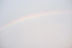 un arc-en-ciel sur le fond du ciel défocalisé en arrière-plan. ciel lumineux défocalisé après la pluie. photo