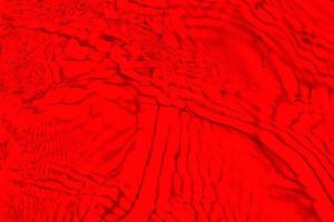 défocalisation floue transparente de couleur rouge clair texture de surface de l'eau calme avec des éclaboussures et des bulles. fond de nature abstraite à la mode. vagues d'eau au soleil avec espace de copie. aquarelle rouge brillant photo