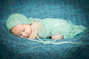 bébé nouveau-né dormant doucement sur un tapis bleu à capuchon bleu photo