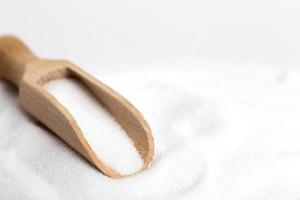 grain de sel en vue de dessus de cuillère en bois sur fond blanc, plat. photo