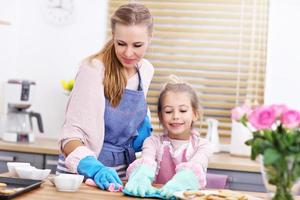 petite fille et sa maman en tabliers nettoyant la cuisine photo