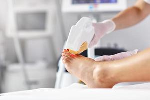 esthéticienne donnant un traitement au laser d'épilation à une femme sur les jambes photo