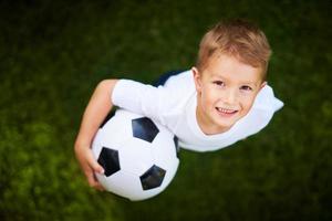 petit garçon pratiquant le football à l'extérieur photo