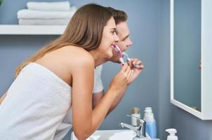 portrait d'un jeune couple heureux se brosser les dents dans la salle de bain photo