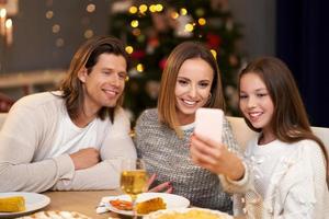 belle famille célébrant noël à la maison et prenant selfie photo