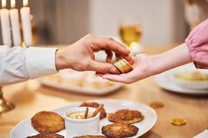 dîner de Hanoucca. se concentrer sur le père qui donne des pièces aux enfants photo