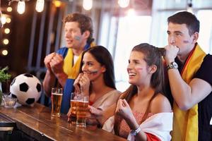 groupe d'amis regardant le football dans un pub photo