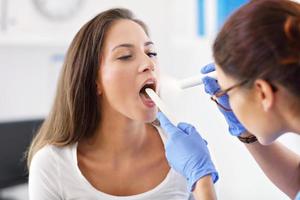 femme adulte ayant une visite au bureau du laryngologue féminin photo