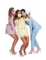 trois femmes en costumes pastel posant avec des smartphones sur fond blanc photo