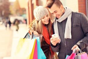 couple heureux shopping dans la ville avec smartphone photo