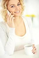 jeune femme avec smartphone et café dans la cuisine photo