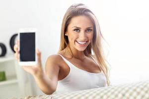 femme heureuse avec smartphone sur canapé photo