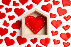 gros plan de coeur rouge dans une maison décorée de petits coeurs sur fond de bois. La Saint-Valentin. concept de maison douce maison photo