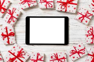 écran vide de tablette numérique avec boîte-cadeau et décor de coeurs sur table en bois. vue de dessus. fond de concept de saint valentin ou d'autres jours fériés photo