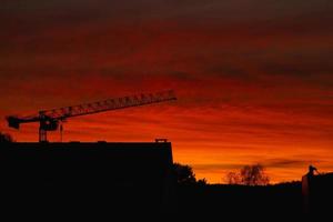 coucher de soleil rouge. silhouette de la ville au coucher du soleil. silhouette de grue contre le ciel rouge photo