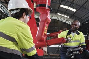 l'équipe masculine d'ingénieurs de production discute, teste et contrôle le bras robotique dans l'usine de fabrication mécanique, les machines automatiques intelligentes dans les entreprises industrielles et l'innovation technologique futuriste. photo