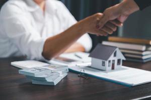 les agents immobiliers proposent des contrats d'achat ou de location d'habitation. mains d'homme d'affaires tenant le modèle de maison, petit bâtiment maison rouge. assurance des biens hypothécaires déménagement et concept immobilier photo