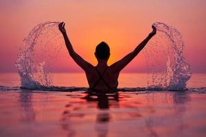 jeune femme nageant dans la mer au lever du soleil photo