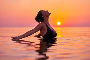 jeune femme nageant dans la mer au lever du soleil photo