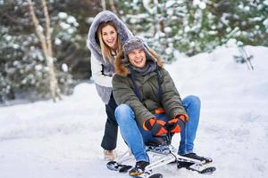 couple s'amusant avec un traîneau sur la neige en hiver photo