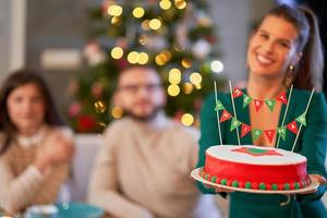 groupe d'amis célébrant noël à la maison avec un gâteau de fantaisie photo