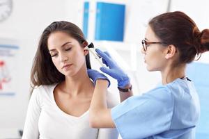 femme adulte ayant une visite au bureau du laryngologue féminin photo