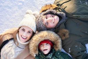belle famille heureuse s'amusant sur la neige d'hiver photo