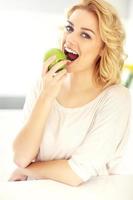 jeune femme mangeant une pomme dans la cuisine photo