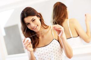 jeune femme utilisant du fil dentaire dans la salle de bain photo