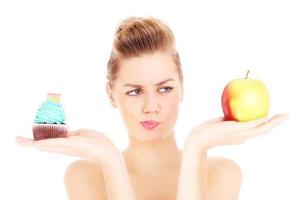 femme essayant de prendre une décision entre cupcake et pomme photo