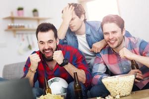 heureux amis masculins acclamant et regardant le sport à la télévision photo