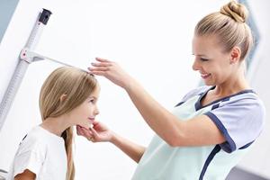 femme médecin mesurant la taille d'une fille à la clinique photo