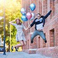 couple adulte tenant des ballons et sautant dans la ville photo