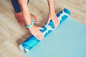 jeune femme roulant un tapis de yoga à la maison photo