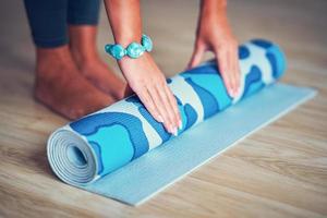 jeune femme roulant un tapis de yoga à la maison photo