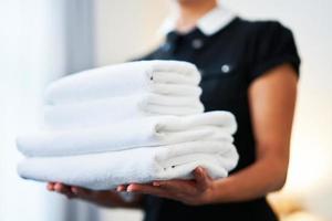 femme de ménage avec des serviettes propres dans la chambre d'hôtel photo