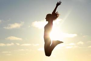 silhouette jeune femme pratiquant le yoga sur la plage au coucher du soleil photo