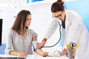 femme adulte ayant un test de pression artérielle lors d'une visite au bureau du médecin féminin photo