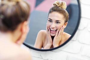jeune femme nettoyant le visage dans le miroir de la salle de bain photo