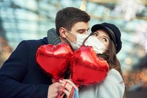 couple heureux célébrant la saint valentin masqué pendant la pandémie de covid-19 photo