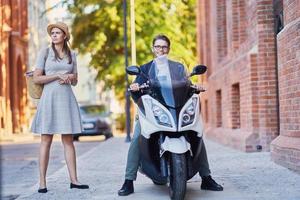 Happy young couple riding a scooter dans la ville par une journée ensoleillée photo