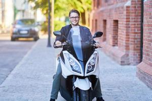 homme heureux faisant du scooter dans la ville par une journée ensoleillée photo