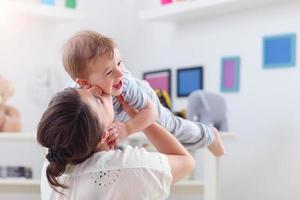 heureuse mère jouant avec bébé garçon à la maison photo