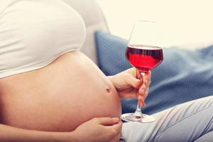 gros plan sur une femme enceinte avec un verre de vin photo