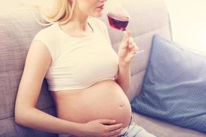 gros plan sur une femme enceinte avec un verre de vin photo