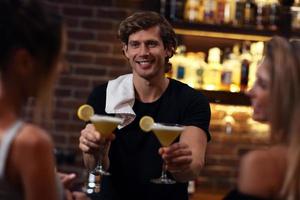 beau barman qui sert des cocktails dans un pub photo