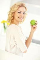 jeune femme mangeant une pomme dans la cuisine photo