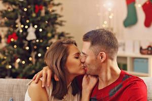 jeune couple s'embrassant sur l'arbre de noël photo