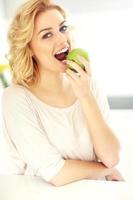 jeune femme mangeant une pomme dans la cuisine photo